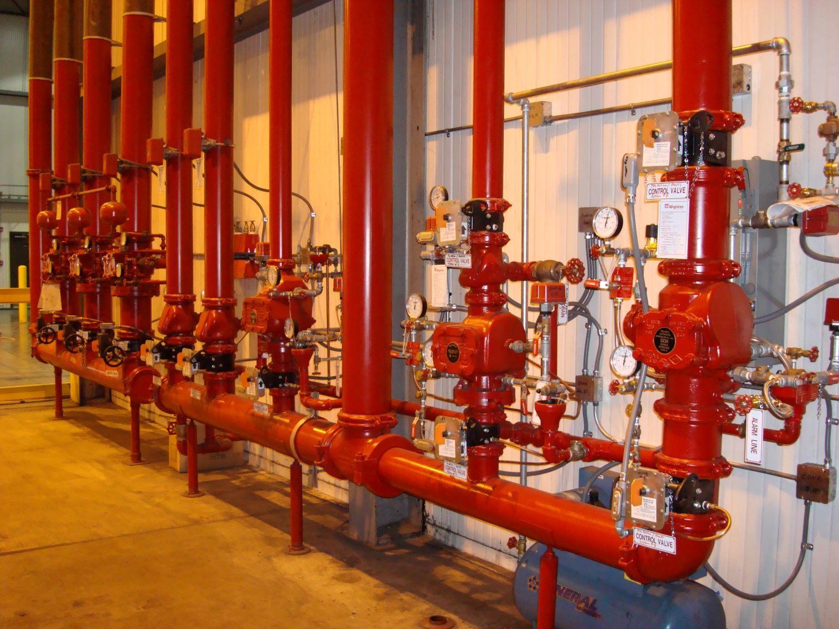 A wall of red sprinkler risers and alarm valves installed by Wiginton